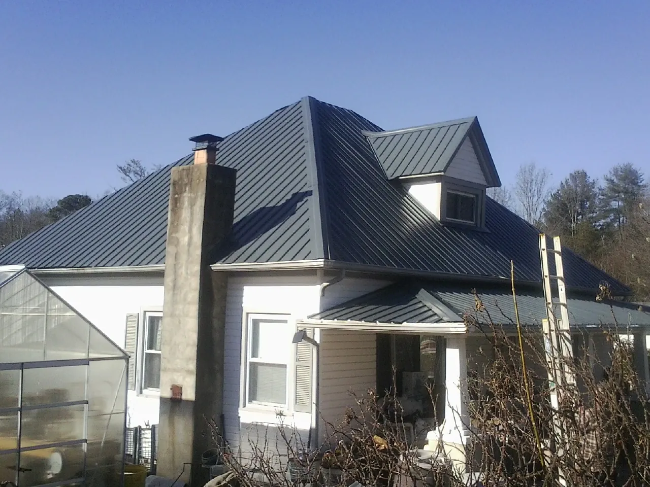 Dark blue standing seam metal roof on a white farmhouse with dormer — Slate & Tile Roof Repair by Roofing Brothers in Good Thunder