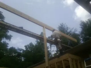 Carpenter setting a ridge beam over a new addition frame — Ice Dam Removal by Roofing Brothers in Good Thunder