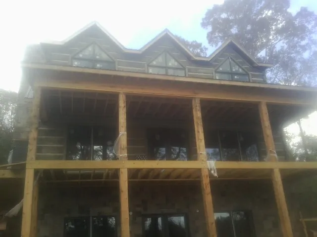 Dormers and porch framing on a large log home under construction — Roof Coating work by our crew in Good Thunder