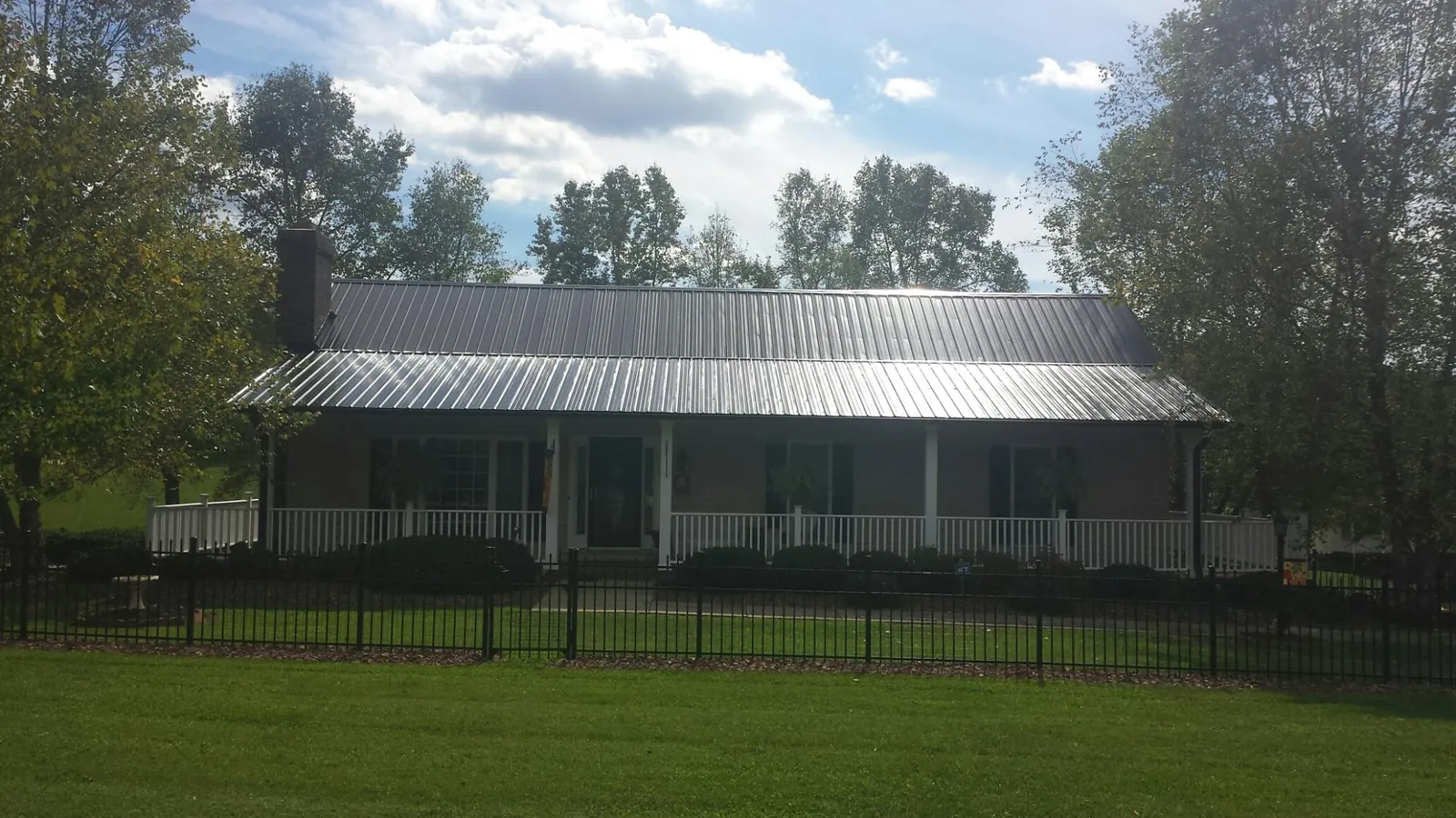 Gray metal roof on a brick ranch with a full width front porch — Gutter Guard Installation work by our crew in Good Thunder